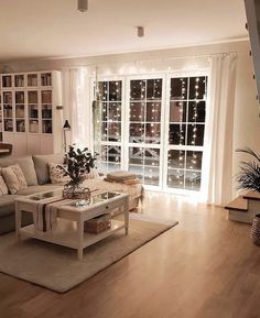 a living room filled with furniture next to a window covered in lights and bookshelves