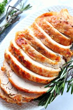 slices of sliced turkey on a white plate with rosemary sprigs and seasoning