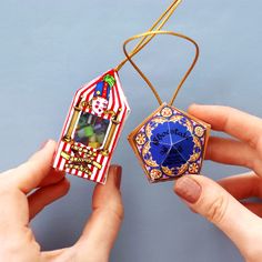 two hands holding an ornament shaped like a candy box