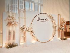 the entrance to an event decorated with white flowers and greenery is surrounded by gold hoop