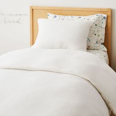 an unmade bed with white sheets and pillows