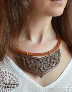 a woman wearing a brown leather necklace with green accents