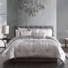 a bed with silver sheets and pillows in a room