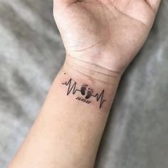 a person's wrist with a dog paw and heartbeat tattoo