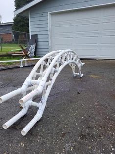 a large white pipe laying on top of a driveway next to a garage door and a house