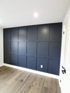 an empty room with dark blue walls and wood floors