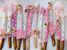 pink and white bees decorated pretzels on sticks