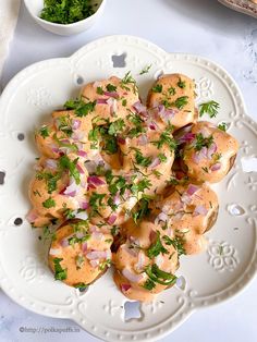 a white plate topped with meat covered in sauce and garnished with parsley