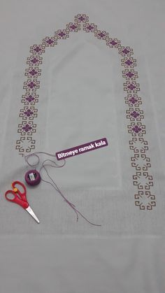 a pair of scissors and some thread sitting on a table cloth with a name tag