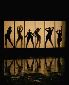 the silhouettes of four women in front of a window with their arms up and hands behind them