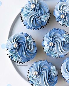 cupcakes with blue frosting and pearls on top are arranged on a plate