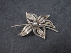 This beautiful flower brooch is sterling silver. Measurements: 1 5/16 by 1 7/8 inches Marks: Forstner, Sterling Condition: Excellent with patina The Forstner jewelry company was founded in 1920 in Irvington, New Jersey. The company later changed their name to the Forstner Jewelry Manufacturing Corporation. In 1980, the corporation ceased operations. Formal Flower Shaped Hallmarked Brooch, Classic Flower Brooches For Anniversary, Silver Flower Shaped Brooch Jewelry, Silver Floral Shape Brooch Jewelry, Silver Flower Shaped Brooch, Silver Floral Brooch, Vintage Sterling Silver Flower Brooches, Elegant Silver Flower Shaped Brooch, Vintage Silver Flower Brooches