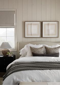 a bedroom with two framed pictures above the headboard and pillows on the bed in front of it