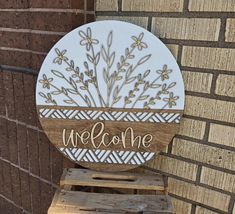 a welcome sign sitting on top of a wooden pallet next to a brick wall