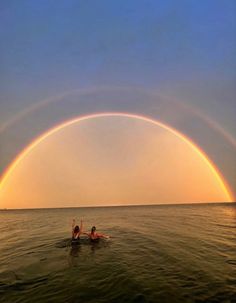 two people in the ocean under a rainbow