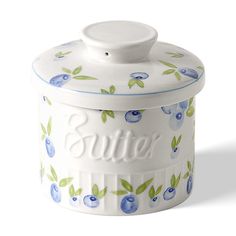 a white and blue canister with an apple design on the lid that says butter