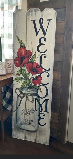 a wooden sign that says welcome with red flowers in a mason jar on the front