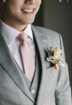 a man in a gray suit with a pink tie and flower boutonniere