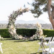 an outdoor ceremony setup with white chairs and flowers