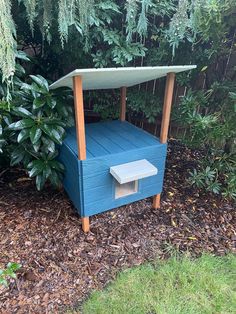 a blue wooden bench in the middle of some bushes