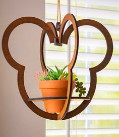 a potted plant is hanging from a mickey mouse shaped shelf with an air planter attached to it