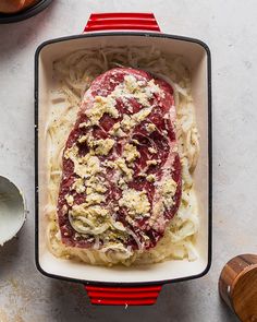 an uncooked steak in a casserole dish with parmesan cheese on top