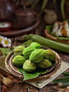 green powdered cookies on a bamboo plate with flowers in the backgroung