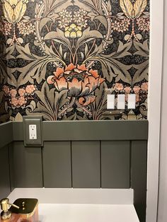 a bathroom with floral wallpaper and gold faucet