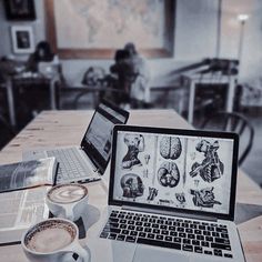 an open laptop computer sitting on top of a wooden table next to a cup of coffee