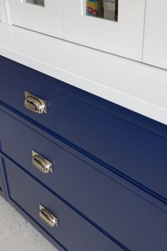 a blue and white dresser with two pictures on the wall above it's drawers