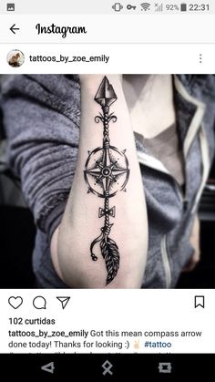 a woman's arm with a compass and arrow tattoo on the left side of her arm