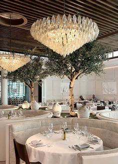 a dining room with tables and chairs, chandeliers hanging from the ceiling