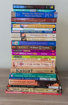 a stack of children's books sitting on top of a wooden table in front of a white wall