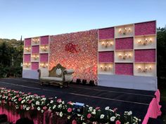 a stage set up for a wedding with pink and white flowers on the floor, lit by candles