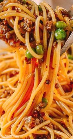 a fork full of spaghetti with meat and vegetables