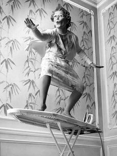 a woman standing on top of a ironing board