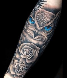 an owl with blue eyes and roses tattoo on the left arm is shown in black and grey