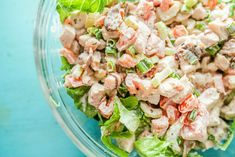 a salad in a glass bowl with lettuce and shrimp on top, ready to be eaten