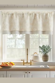 a kitchen sink under a window next to a vase with flowers and fruit on it