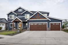 a blue house with brown garage doors and windows