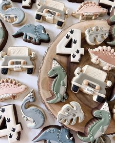 decorated cookies with cars and dinosaurs are on a wooden plate next to the number four