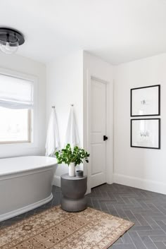 a bathroom with a tub, rug and pictures on the wall