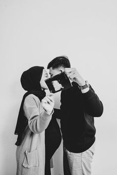 two people standing next to each other taking pictures