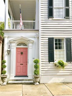 a white house with a pink door and black shutters