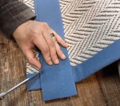 a person cutting fabric with scissors on a wooden table