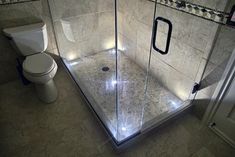 a bathroom with a walk in shower next to a white toilet and tiled flooring