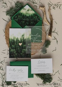 the wedding stationery was done in green and gold, with pine - covered evergreens