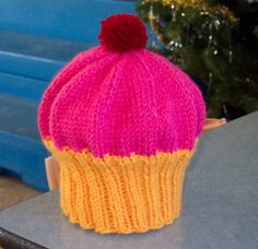 a pink and yellow knitted hat sitting on top of a table