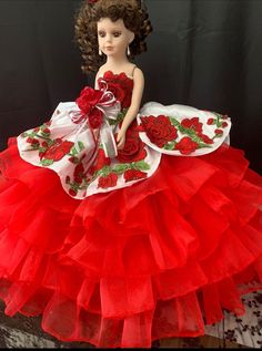 a red and white dress with roses on the skirt is sitting on top of a table