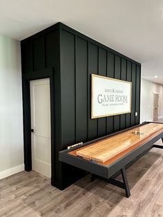 a game room with a shuffle table in the center and a sign on the wall